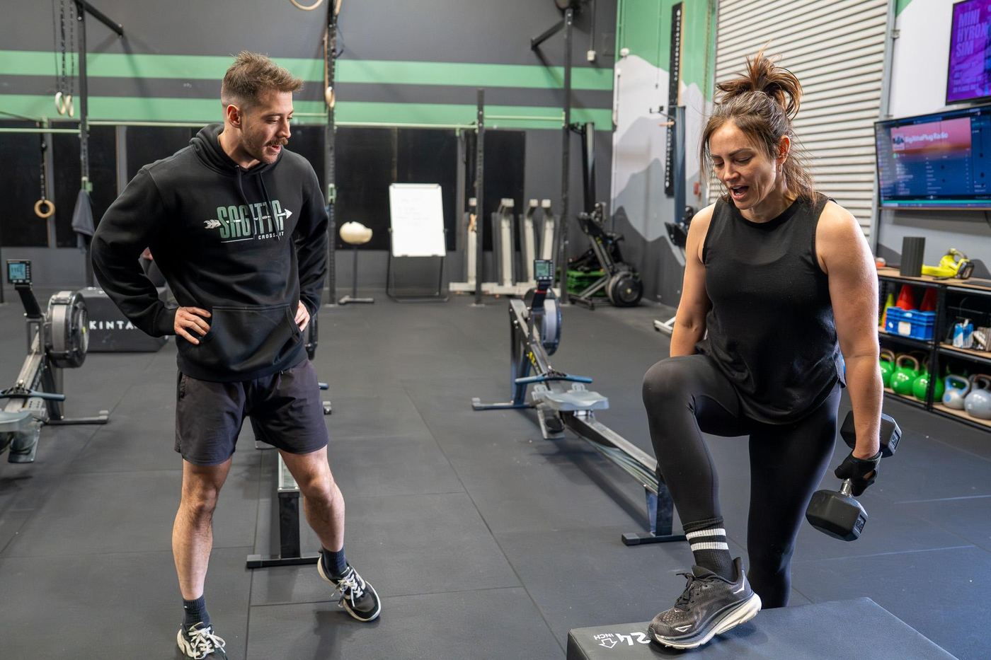 A Sagitta coach guiding a member through a step-up
