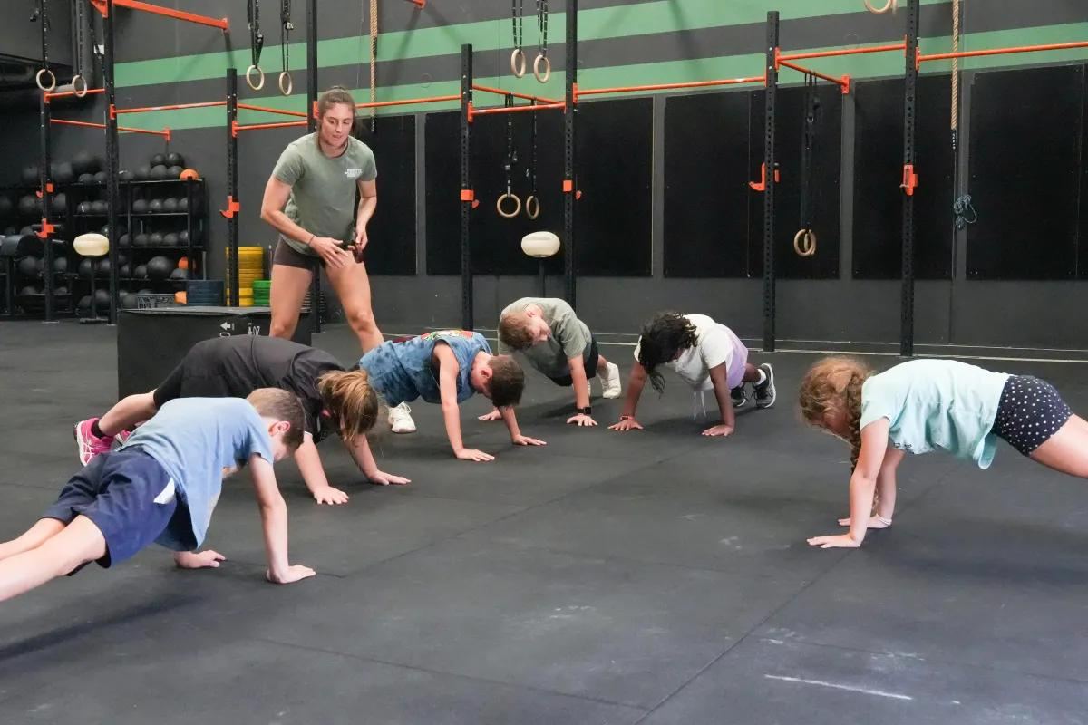 Kids doing push-ups in a coached CrossFit Kids class