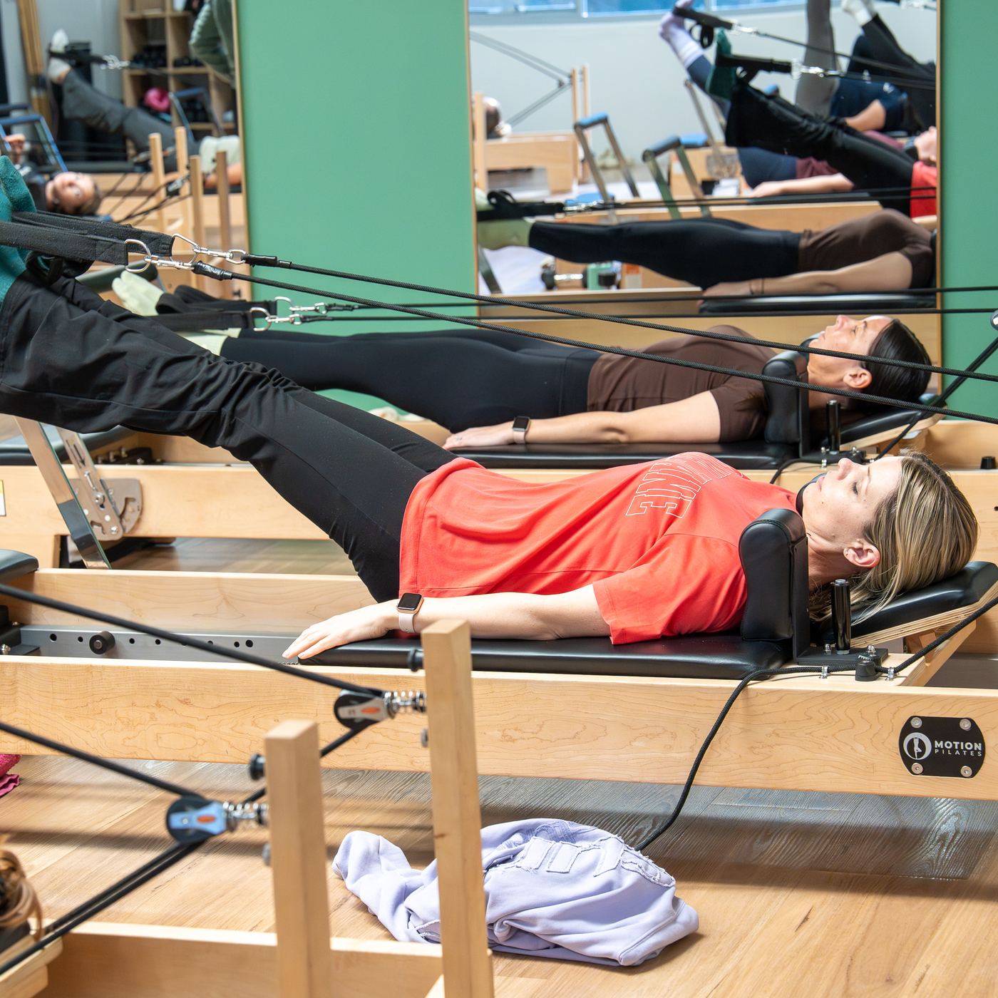 Members lying on reformers during a Pilates class